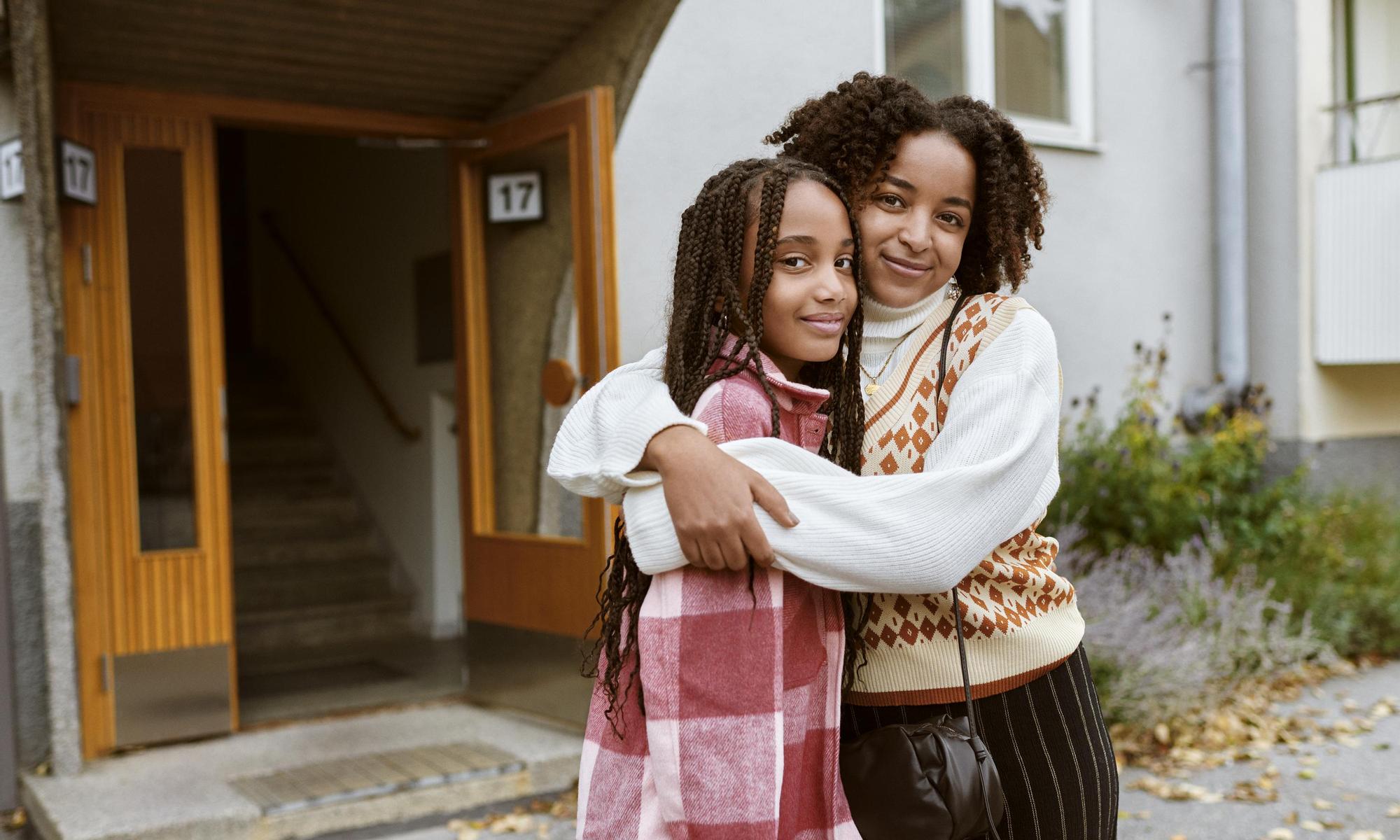 Mother and daughter hugging outside apartment