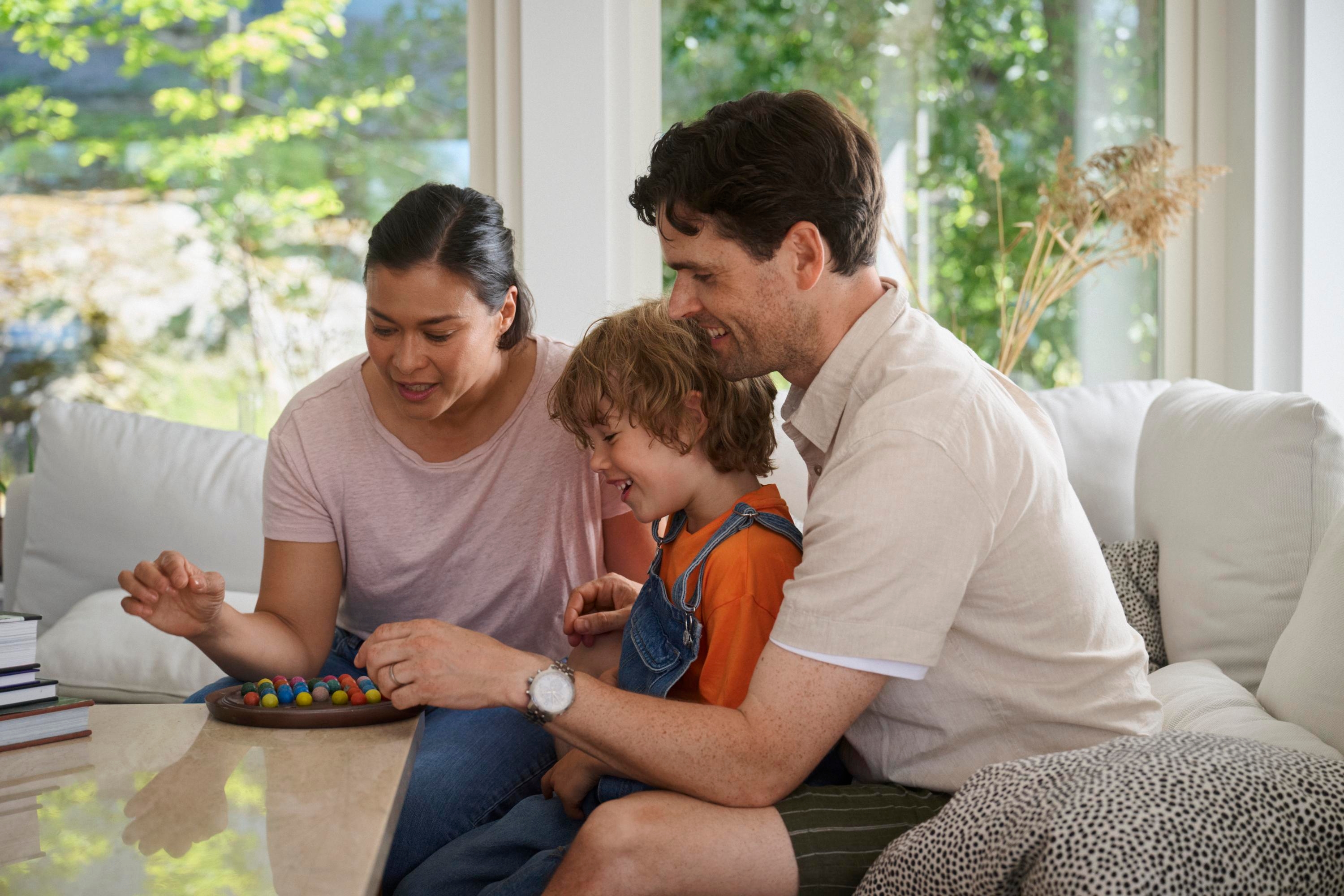 Två vuxna och ett barn spelar brädspel tillsammans