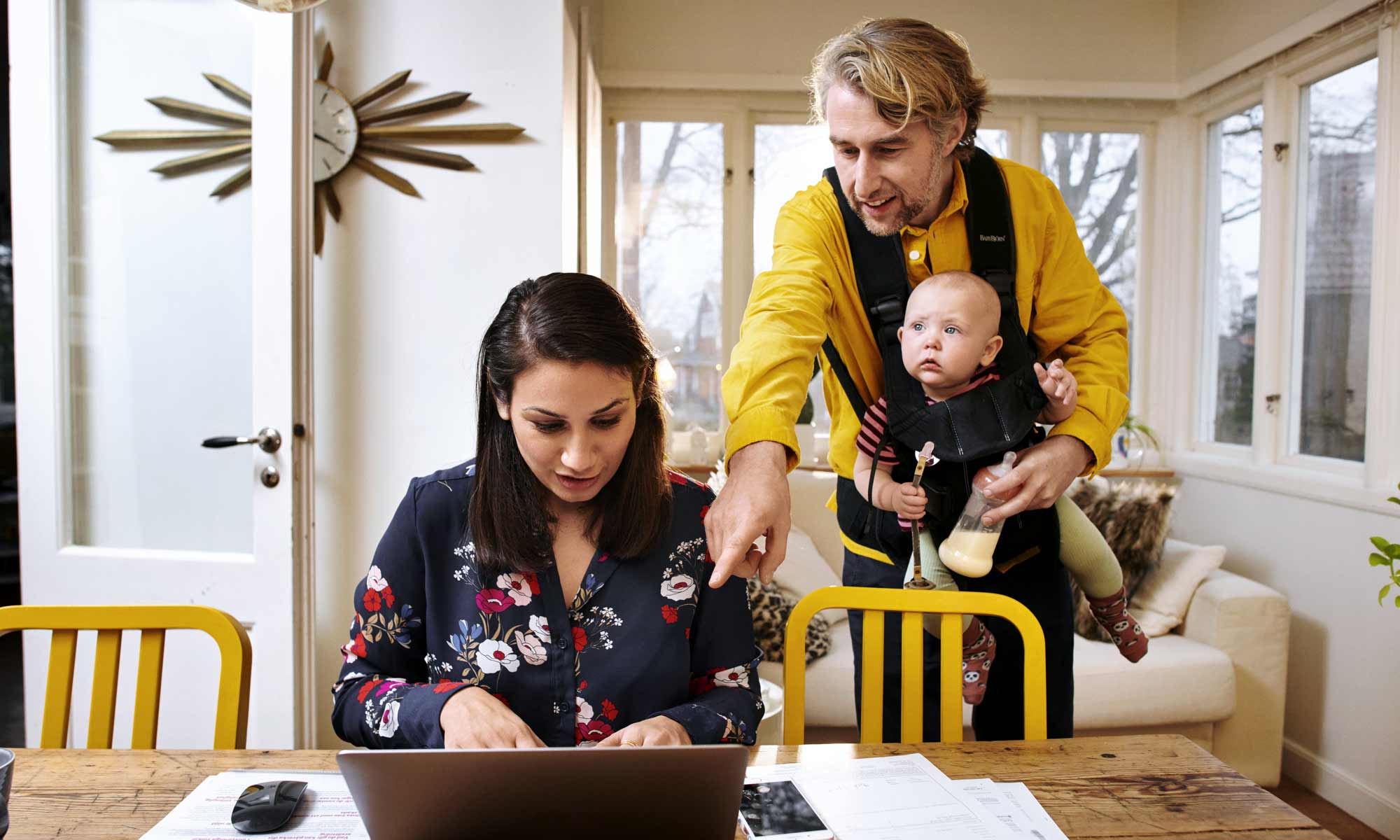 Ett par med en bebis tittar på en laptop.